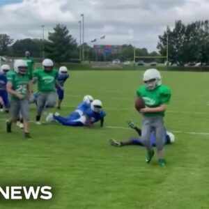 Elementary school football teams come together to set up special play for teammate